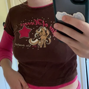 y2k tröja - jätte snygg 2000-tals tröja med tryck. Bra skick och inga kristaller eller så saknas. Har visa detaljer som är sammet. Bra skick förutom lite av tyget är sprucket. Kan passa S men skulle sitta bekvämare på XS eller mindre. Då det är en barnstorlek 128. Färgen är mörkbrun som på de två första bilderna. Köparen står för frakt. 💕