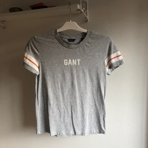 T-shirt från Gant! - Grå tischa från Gant med vita och orangea detaljer på ärmarna. Använd endast 3ggr! 💕 Fraktkostnad, 60kr 💕