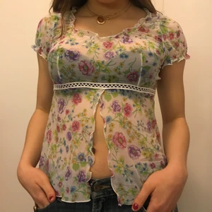 Blommig top - Söt topp/blus med blommor, lite genomskinlig. Går att ha som den är men går även att knyta. Är i storlek L men funkar även för folk som har S och upp