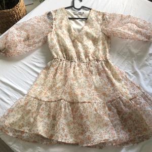 Blommig puffig vårkänning NA-KD - En underbar vår/sommarklänning från NA-KD som är helt oanvänd och köptes för 600 kr. Den sitter perfekt på midjan tack vare elastiska bandet och passar strl 34-36 samt en liten 38. Den är puffig och är lite längre än en miniklänning. DM för mer information/bilder!