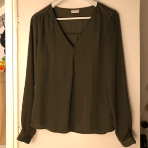 Grön blus  - Militärgrön blus i stl XS från vila med en söt liten detalj framtill. Första bilden missvisar färgen lite den e mer som på den andra bilden. Använd fåtal gånger så i fint skick, säljs då den inte kommer till användning💕 Köparen står får frakten 