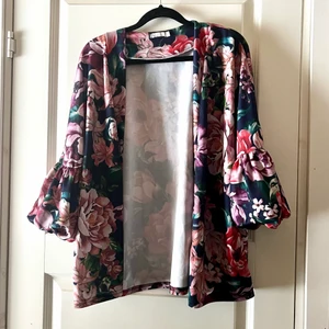 Blommig jacka - Blommig jacka med ballongärmar från NLY Trend i strl L. Använd ett fåtal gånger. Det har funnits ett band till midjan men jag har tyvärr tappat bort det men den är snygg även utan bandet.