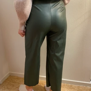 Läderbyxor, läderimitation - Stilrena mörkgröna läderbyxor (läderimitation) i fint skick, endast använda 1 gång!! Dragkedjan på sidan. 