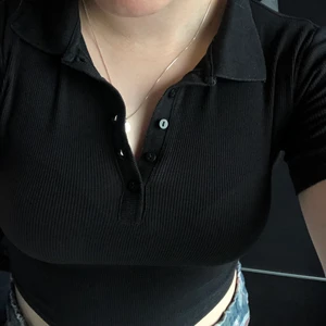 Svart ribbad ZARA topp - Svart ribbad kortärmad topp från Zara. Det står M på lappen men den är mer en XS/S i storlek. Den är väldigt stretchig så passar även mig som är en M. Den är croppad och har en krage och knappar. 50kr + frakt