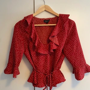 Volangtopp - Supersöt volangtopp från Topshop i kortare modell. Röd med vita prickar. Knytning i midjan. Nyskick