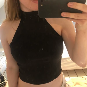 Topp storlek S - Svart, ribbad och croppad topp från NA-KD. Hög krage som stängs med två knappar i nacken. Liten cutout under knapparna i ryggen 😇💚 kan självklart posta den, men köparen står för frakt 🌟