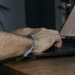 Armband gjord av tjock ståltråd och med kulhöljen. Armbandet design är gjord för att liknad taggtråd.  