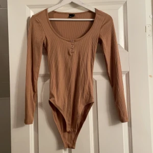 Beige body - En snygg beige body i storlek xs. Denna body passar även xs-s då den har stretch och anpassar sig till kroppsformen. Den passar alla tjejer där ute som gillar en snygg passform som visar ens former och är bekväm. Den är OANVÄND och i väldigt bra skick. 