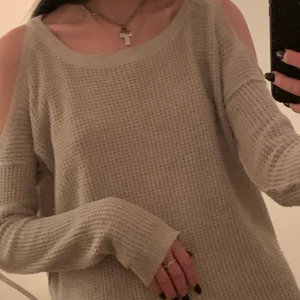 stickad biege tröja - Charmig stickad tröja utan axlar med unika utvrängda sömmar på axlarna. Köpt på Hollister i frankrike, sitter lite oversize för att vara en xs. Her mig lite fairy vibez🧚‍♀️