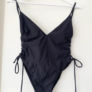 Baddräkt från Zara strl S - Svart snygg baddräkt från zara med djup rygg och knytning i sidan. Köpt för några år sedan men aldrig använd. Strl S men passar xs-s. 