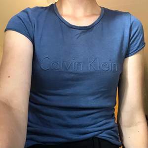 En marinblå t-shirt från Calvin Klein i stolek XS som säljs på grund av att den inte används tillräckligt.