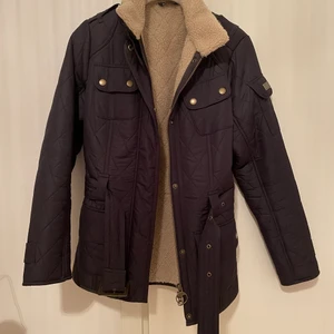 Barbour Höstjacka - Jacka från Barbour i Marin blå med skärp, fickor och ullfodrad på insidan och är i UK Storlek 8.  Knappt använd så den är i super bra skick! 