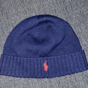 Ralph lauren mössa  - En mörkblå Ralph lauren mössa som knappt är använd och inte ett dugg sliten.