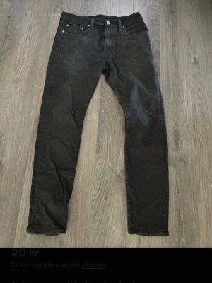 Svarta Levi's jeans  - Säljer ett par klassiska svarta jeans från Levi's med raka ben och femficksmodell. Jeansen har normal midja och silverfärgade nitar. Materialet är denim i bomull. Perfekta för en stilren och enkel look.
