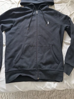 Svart hoodie från Polo Ralph Lauren - Vid snabb affär går det att förhandla. Storlek S mycket bra skick.    Klassisk svart hoodie med dragkedja från Polo Ralph Lauren. två fickor framtill och den ikoniska vita logon broderad på bröstet. 
