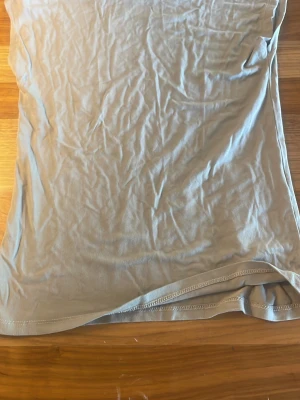 Beige ärmlös linnetopp - En enkel och stilren beige linnetopp i mjukt material. Toppen är ärmlös och har en rak passform, perfekt att matcha med jeans eller kjol för en avslappnad look.