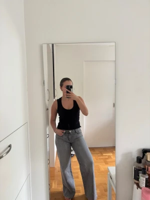 Gråa vida jeans - Säljer ett par gråa jeans med medelhög midja och raka, vida ben. Jeansen har klassisk femficksdesign och knappgylf. Använda fåtal gånger så de är i princip som nya. Byxorna passar även en storlek 36 beroende på hur man vill att de ska sitta