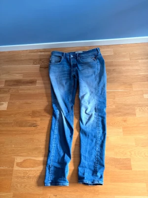 Blå Replay jeans med raka ben - Snygga blå jeans från Replay med klassisk femficksdesign och raka ben. Jeansen har ljus tvätt och diskreta slitningar framtill. Märkespatch i läder baktill och broderad detalj på bakfickan. Perfekta för en avslappnad och trendig look. Hål i pungen🤲🏼🤝 