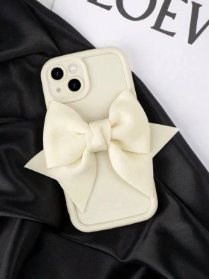 Krämvitt mobilskal med stor rosett Iphone 12 pro max - Snyggt mobilskal i krämvit färg med en stor dekorativ rosett på baksidan. Skalets material är troligtvis mjuk plast eller silikon och ger mobilen en unik och trendig look. Perfekt för dig som vill sticka ut och addera lite extra stil till din telefon. 