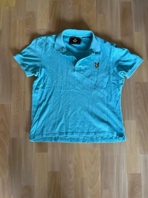 Turkos/ Ljusblå Lyle & Scott Piké – Strl L Herr  - Lyle & Scott Piké – Strl L  Klassisk pikétröja från Lyle & Scott i snygg ljus turkos färg med broderad örnlogga på bröstet. Perfekt till sommaren och lätt att matcha med både shorts och jeans. Strolek L Färg: Ljus turkos Skick: Gott skick