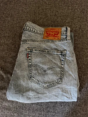 Levi's 514 ljusblå raka jeans - Säljer ett par klassiska Levi's 514 jeans i ljusblå tvätt med raka ben och femficksmodell. Jeansen har den ikoniska röda Levi's-lappen på bakfickan och patch i läder bak i midjan. Perfekta för en avslappnad och tidlös stil. Knappt använda