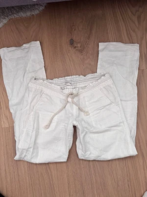 Vita linnebyxor från Roxy - Snygga vita linnebyxor från Roxy med avslappnad passform och dragsko i midjan. Byxorna har fickor fram och är tillverkade i ett lätt och luftigt linnematerial, perfekta för en chill och stilren look. Kom med prisförslag 