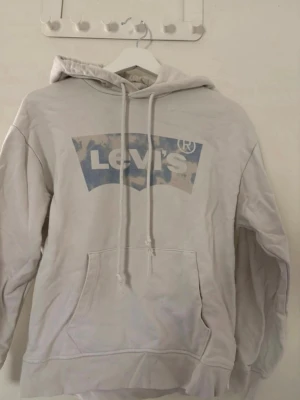 Levis hoodie  - Vit hoodie från Levi’s med blått logotryck framtill. Supermjuk och skön passform, perfekt till både vardag och mys. Använd men i fint skick 