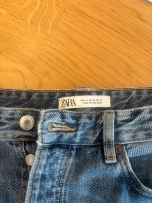 Blå raka jeans från ZARA - Snygga blå jeans från ZARA med klassisk femficksmodell och raka ben. Jeansen har en ljus tvätt och silverfärgade knappar. Perfekta för en avslappnad och trendig look.