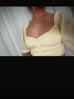 Crop top / Topp - Ljusgul crop top med mindre ballongärmar och knyt fram. Går att ha of shoulder och vanligt. Går att ändra hyr mycket crop top och hur urringad den blir genom att dra åt snörena.
