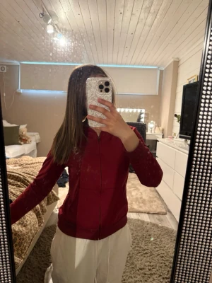Vinröd hoodie med dragkedja - Säljer en vinröd hoodie med dragkedja framtill och fickor på magen. Hoodien har en klassisk huva och ribbade muddar vid ärmslut. Obs: kommer från shein 