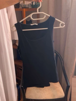 Svart linnetopp från Zara - En enkel och stilren svart linnetopp från Zara. Toppen är ärmlös med rund halsringning och har en klassisk, rak passform. Perfekt att matcha med jeans eller kjol för en clean look.