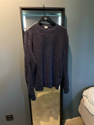 Mörkblå stickad tröja - Mysig mörkblå stickad tröja med rund halsringning och långa ärmar. Perfekt för kyligare dagar och enkel att matcha med olika outfits.
