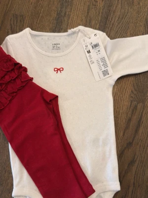 Vitt bodyset med rosett från Lindex - Baby Girl lindex set. Size 74. New and tagged. Size is 74. Bought for 279kd.