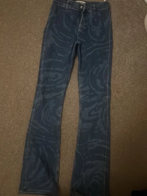 Blå mönstrade bootcut jeans från ONLY - Säljer ett par blå bootcut jeans från ONLY med unikt swirl-mönster över hela byxan. Jeansen har klassisk femficksdesign, hällor för bälte och dragkedjegylf. Perfekta för dig som vill sticka ut med en cool och trendig look. (Pris kan diskuteras)💕