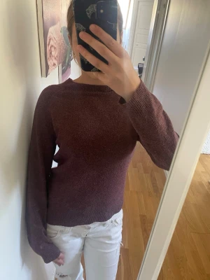 Mörkröd stickad tröja - Mysig mörkröd stickad tröja med rund halsringning och långa ärmar. Tröjan har en enkel och stilren design med ribbade muddar vid ärmslut och nederkant. Perfekt för lager-på-lager och passar till både jeans och kjol.