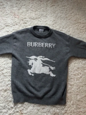 Stickad tröja - En stilren mörkgrå stickad tröja med rund hals och långa ärmar. Tröjan har ribbade muddar vid ärmslut och nederkant, perfekt för att hålla värmen. Passar dig som gillar en klassisk och clean look.