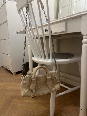 Beige handväska med kedjerem - Cool beige handväska med slitna detaljer och kedjerem. Väskan har två handtag och är tillverkad i ett tygmatrial. Kommer från Zara men köpte på en loppis, bara andvänt en gång❤️ 