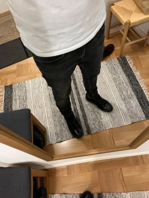 Tiger of sweden jeans  - Säljer ett par svarta slim fit jeans med klassisk femficksdesign och diskreta slitningar. Jeansen har normal midja och smal passform hela vägen ner. Perfekta till sneakers eller boots för en clean och modern look.