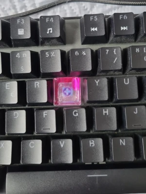 Keycap rosa till tangentbord - Säljer en transparent rosa keycap av epoxy som passar mekaniska tangentbord med korsfäste. Perfekt för dig som vill ge ditt tangentbord en personlig touch och sticka ut lite extra. Keycapen är fyrkantig och har en modern look.