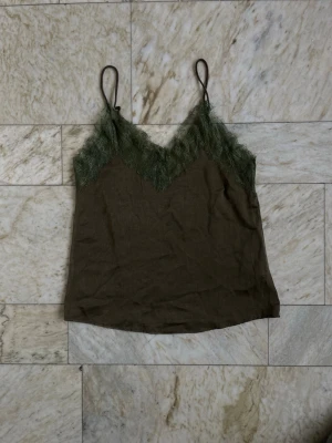 Spetslinne - Spetslinne i olivgrön färg 🍸 Justerbara band OBS i verkligheten är det inte så stor nyansskillnad på spetsen och satintyget