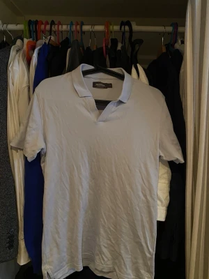 Ljusgrå pikétröja från J.Lindeberg - Klassisk ljusgrå pikétröja från J.Lindeberg med korta ärmar och krage. Tillverkad i mjuk bomull som känns skön mot huden. Perfekt till jeans eller shorts för en clean och enkel look.