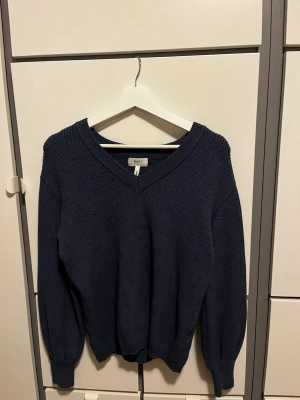 Mörkblå stickad tröja från Object - Mysig mörkblå stickad tröja från Object med v-ringad hals och ribbade muddar. Tröjan har en avslappnad passform och är perfekt för kyliga dagar. Klassisk design som passar till det mesta i garderoben.