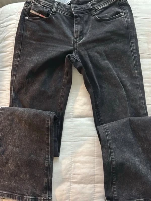 Svarta raka jeans från Diesel - Säljer ett par svarta jeans från Diesel med rak passform och klassisk femficksdesign. Jeansen har en tvättad look och är tillverkade i denim med en liten logga på myntf annotation. Perfekta för en avslappnad och trend surviv.