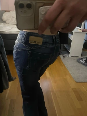 Blå low waist bootcut jeans  - Säljer ett par blå bootcut jeans från klassiska kontrastsömmar och med låg midja.  Jeansen har en snygg tvätt med slitningar och fem fickor. De är lågmidjade och omsydda till bootcut. 