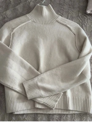 Beige stickad polotröja - Säljer en beige stickad polotröja med ribbade muddar och hög krage. Materialet känns mjukt och skönt mot huden och int alls stickigt . Enkel och stilren design som passar till det mesta.     Säljs då den int kommer till användning. Liten i storleken så skulle säga att de är mer som en S/m