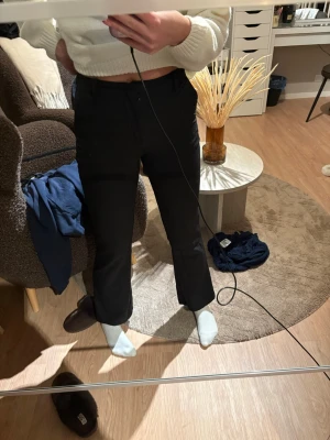 Svarta kostymbyxor med raka ben - Snygga svarta kostymbyxor med klassisk rak passform och medelhög midja. Byxorna har diskreta fickor i sidorna och hällor för skärp. Perfekta för en stilren look och lätta att matcha med olika toppar.