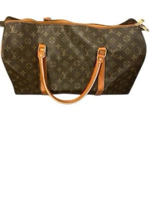  Resväska - Stilren resväska i klassiskt brunt monogrammönster med logga. Väskan har två långa handtag i läder och dragkedja med guldfärgad detalj. Tillverkad i canvas och läder, perfekt för weekendresor.