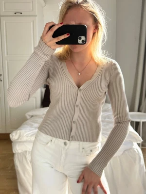 Beige ribbad kofta med knappar💖💖 - Snygg beige ribbad kofta med v-ringning och långa ärmar. Koftan har en figurnära passform och stängs med knappar framtill. Perfekt att styla med jeans eller kjol för en clean look.