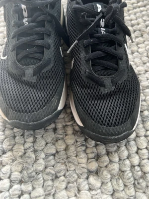 Svarta Nike Air Max sneakers - Snygga svarta Nike Air Max sneakers med vit sula och vit swoosh på sidan. Ovandelen är i mesh för bra ventilation och skon har klassisk snörning. Perfekta för dig som gillar sportig stil och vill ha bekväma skor till vardags.