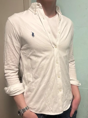 Vit Ralph Lauren skjorta – S - Säljer denna stilrena och snygga vita Ralph Lauren skjortan. Skjortan är i  bra skick. Storlek s/p vilket motsvarar ca M slim fit. Är i i skönt piké material. Har du några frågor? Tveka inte att höra av dig. Allt got Deluxe Garderoben ⭐️